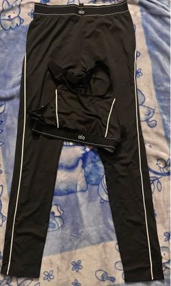 black and Grey alo Yoga leggings and a matching sports bra with white piping