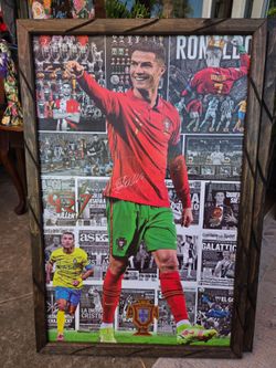 A wood-framed decorative picture featuring a collage of photos, trophies, and press clippings of footballer Cristiano Ronaldo.