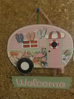 Colorful camper-shaped welcome sign with flip-flops and flamingo design.