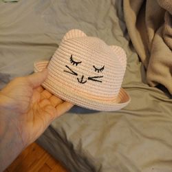 A Pink Straw Hat With Animal Face Highlighted In Black It Also Has Two Ears