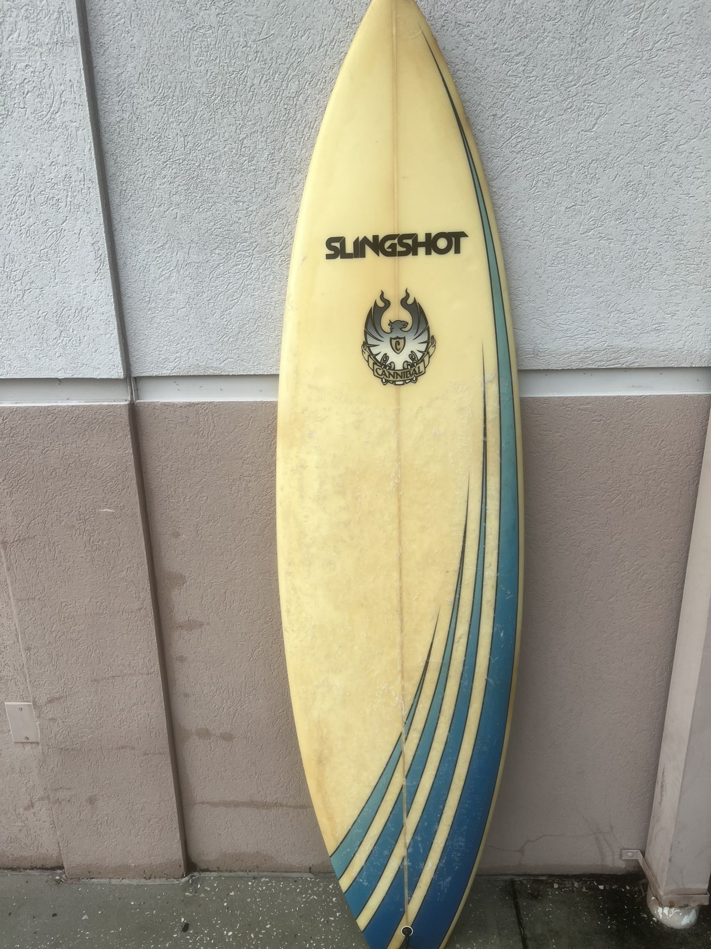 6fVintage Slingshot surfboard W/ Cannibal graphic. Used in good condition with some areas of patches. Despite the patches the top is still in great c