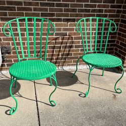 two green wrought iron patio chairs