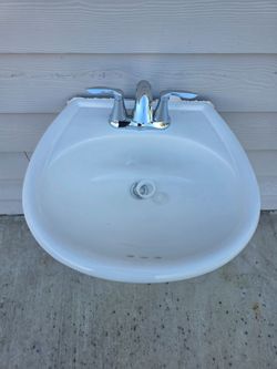 White Pedestal bathroom sink with hardware and chrome faucet