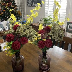 Two purple vases with faux flowers.