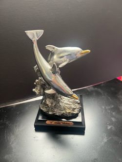 silver-toned sculpture of two leaping dolphins on a rocky base from the "W. Ania Collection"