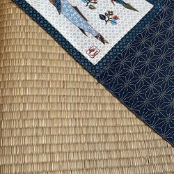 traditional Japanese tatami mat, typically made from woven rush grass around a compressed straw core, featuring a decorative fabric border. 
