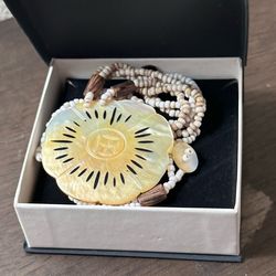 Vintage-style multi-strand beaded necklace featuring a large, carved mother-of-pearl shell pendant