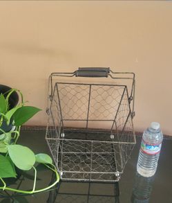 FARMHOUSE-STYLE RUSTIC METAL AND WIRE BASKET WITH WOODEN FOLD-DOWN HANDLES.