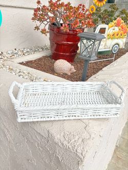 white wicker or rattan rectangular serving tray with side handles.