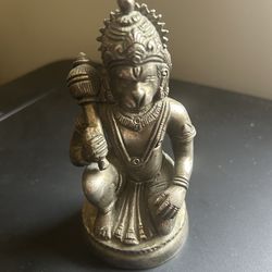 brass statue of the Hindu deity Hanuman, depicting him in a kneeling posture holding his traditional weapon, the gada