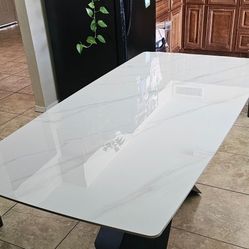 Modern marble-look dining table with sculptural black X-base.
