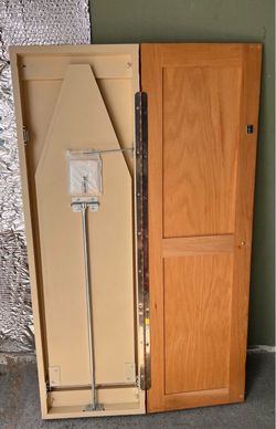 Wall-mounted wooden cabinet with a fold-away, concealed ironing board.