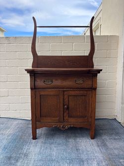 Antique oak washstand featuring a distinctive lyre-shaped top with a hanging bar and brass drawer pulls
