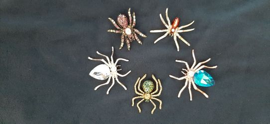 Decorative spider brooches with gemstones.