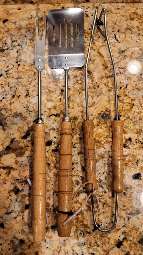 Barbecue grilling tools, likely made of stainless steel with wooden handles.