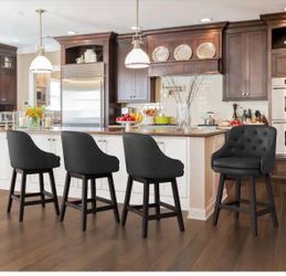 Set of four 67 cm (26.5-inch) solid wood and black faux leather swivel bar stools (counter height), featuring double cushioning and nailhead trim.