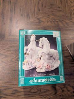two white porcelain unicorn figurines with flower accents from the fantasies collection