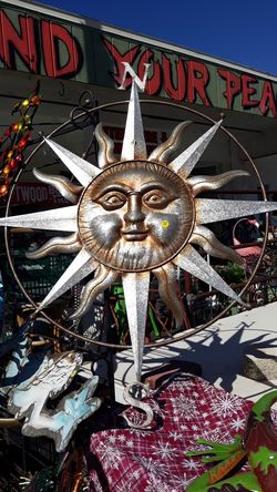 Large metal Sun face with compass surrounding it