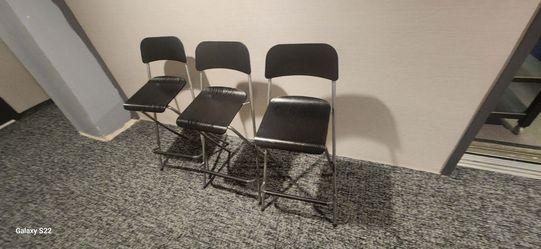 Set of 3 black IKEA Franklin foldable bar stools with metal frames.