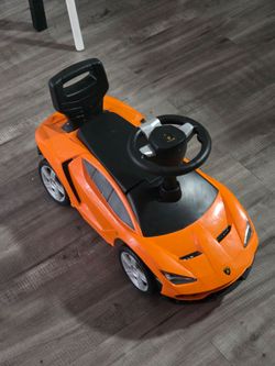 Este es un coche correpasillos naranja de la marca Lamborghini.