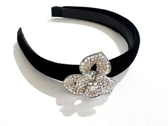 Black velvet headband with a striking, oversized three-petal rhinestone flower.