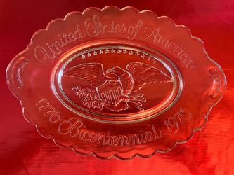 Vintage Avon clear glass Bicentennial commemorative plate featuring an embossed eagle and shield in the center.