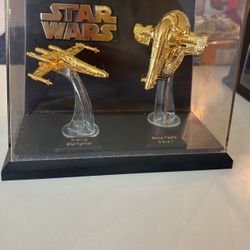 Gold Star Wars Starfighter and Slave I models in a display case