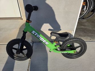 Strider 12 Sport Balance Bike in green features ultralight wheels and tool-free height adjustment.