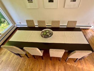 Dramatic, modern large dining room table with eight upholstered chairs