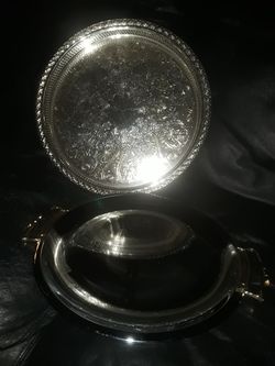 Two serving trays. The more ornate is INTERNATIONAL SILVER COMPANY 14 INCH HAND CRAFTED MADE IN USA. AND OTHER IS KROMEX CHROME & BRASS 13" USA