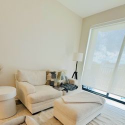 Beige 2-seater sofa with matching ottoman. Comes with two cushions. In good condition, comfortable, and ready to go.