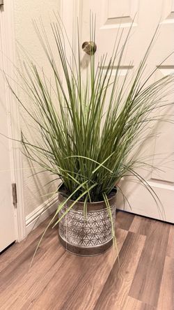 Tall artificial grass plant in a metal pot