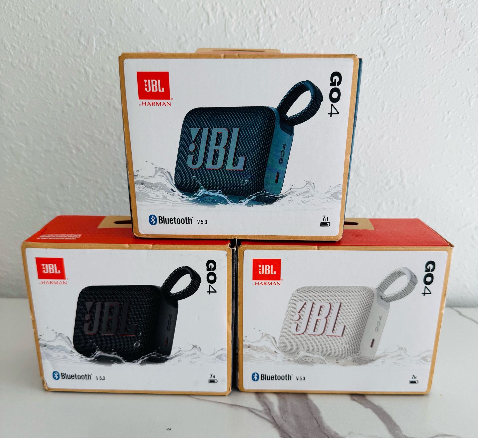 New JBL GO4 portable speakers come in blue, black, and white. Each unit has Bluetooth v5.3 technology and provides 7 hours of playtime. These compact
