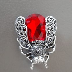 Brooch with a red gem and intricate silver detailing.