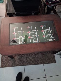 Wooden foosball coffee table features a glass top and cherry wood color