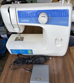 Reliable Brother LS-2125i sewing machine is white with blue accents. This unit includes a foot pedal and power cord. It has a built-in storage compart