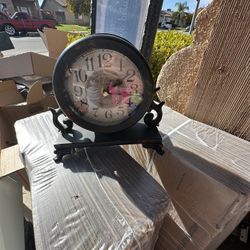 This is a black metal "Old Town Clocks" analog table clock with scroll accents