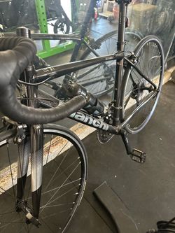 Sleek Bianchi Via Nirone 7 road bike has a black aluminum frame with silver accents. This bicycle is equipped with Tektro rim brakes and Velomann comp