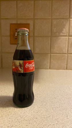 This item is an unopened vintage Coca-Cola Classic Christmas holiday glass bottle