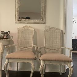 Vintage  French country cane-back armchairs with distressed cream wood and classic Louis-style curves.