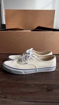 Vans Authentic cream colored canvas sneakers with white laces and a black midsole stripe.