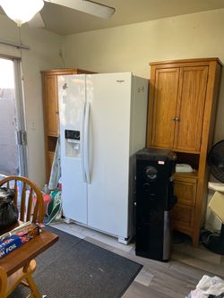 White Whirlpool side-by-side refrigerator. This appliance has a vertical freezer on the left and a refrigerator compartment on the right. It is equipp