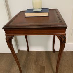A mahogany side table with a hand-tooled leather top and carved cabriole legs.