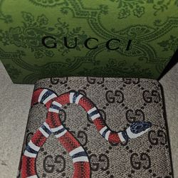Gucci Bifold Wallet in GG Supreme Kingsnake. It is crafted from beige and ebony GG Supreme canvas, which is an environmentally conscious material, and