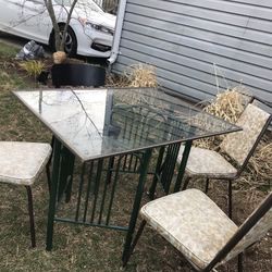 Three Old Fashioned , Vintage  Chairs  With A Black  Chair, With  A Nice Glass Table With  Two Green Bottoms