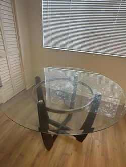 round dining table featuring a tempered glass top and a dark espresso solid wood base.