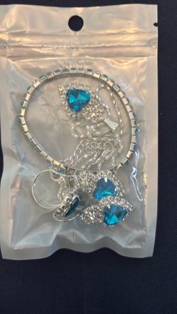 Silver bracelet with blue gems, silver necklace with blue heart and crystal gems in it blue earrings with hearts, blue gems, and a ring with a blue he