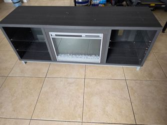 Modern dark wood TV stand with built-in electric fireplace and heater. Excellent condition, features glass shelving and beautiful lighting. Centro de 