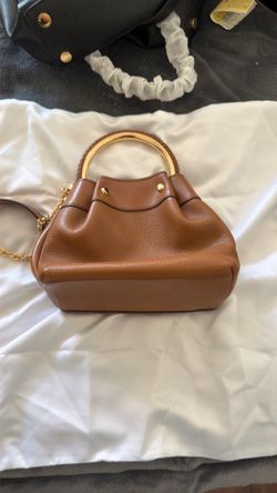 This brown Michael Kors handbag features a distinctive braided top handle and gold-tone chain accents