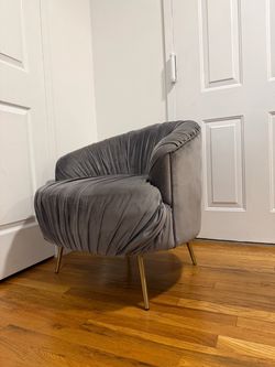 Grey velvet ruched barrel accent chair with gold-finished metal legs.